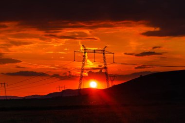 Elektrik kuleleri ve tepeler ile dramatik günbatımı gökyüzü