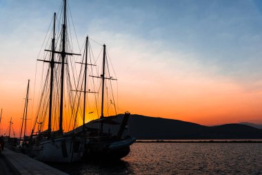 Dramatik gün batımı gökyüzüne karşı gemilerle liman