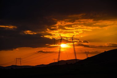 Elektrik kuleleri ve tepeler ile dramatik günbatımı gökyüzü