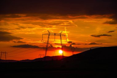 Elektrik kuleleri ve tepeler ile dramatik günbatımı gökyüzü