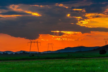 Elektrik kuleleri ve tepeler ile dramatik günbatımı gökyüzü