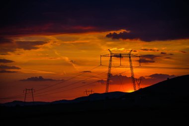 Elektrik kuleleri ve tepeler ile dramatik günbatımı gökyüzü