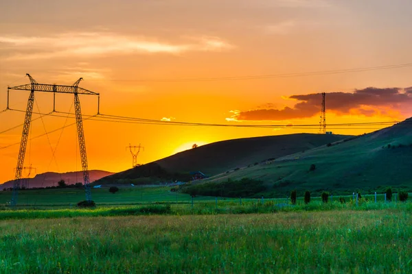 Elektrik kuleleri ve tepeler ile dramatik günbatımı gökyüzü