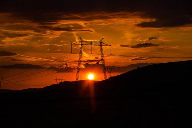 Elektrik kuleleri ve tepeler ile dramatik günbatımı gökyüzü