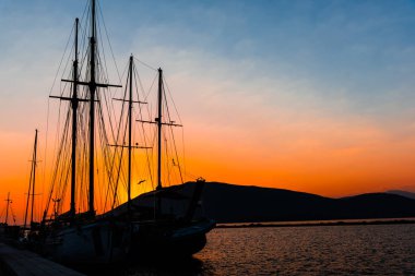 Gün batımı gökyüzü altında limanda Demirli tekneler