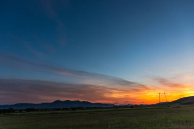 Elektrik kuleleri ve tepeler ile dramatik günbatımı gökyüzü