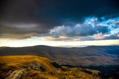 dramatik bulutları ve mavi gökyüzü olan dağ manzarası