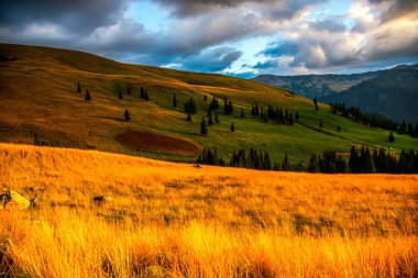 Bulutlu ve güneş ışınlı dağ manzarası