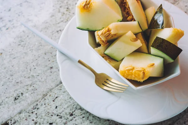 Melon toad skin cut in geometric bowl, on granite countertop, Colorful summer theme