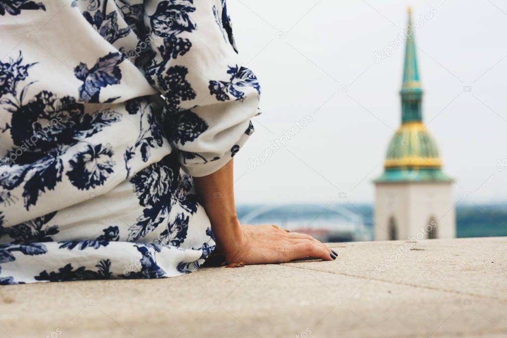 Woman sitting looking at the city skyline with St. Martin's Cathedral, Bratislava, Slovakia -
