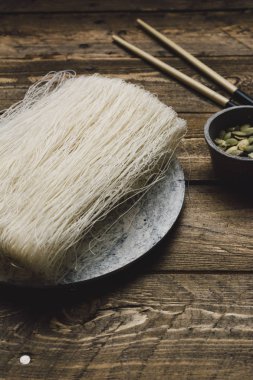 Ahşap rustik masa üzerinde mermer tabak içinde Asya pirinç pişmemiş makarna