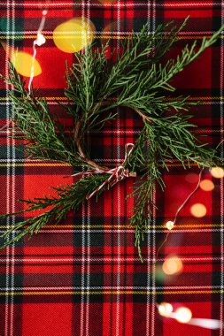 Kırmızı damalı kumaş taze çam dalları Noel çelenk, ve odak ışıkları dışında. Noel kavramsal arka plan.