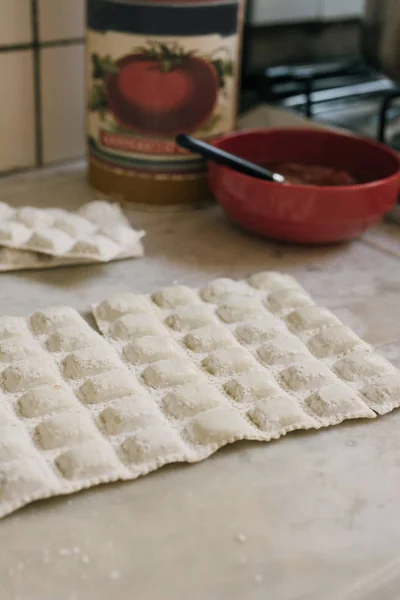 Traditional raw ravioli, on the marble of the kitchen, ready to boil on fire