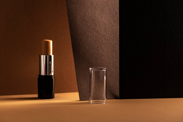 concealer stick, on geometric backgrounds, in shades of brown. Product and makeup concept.