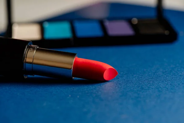 Pink lipstick and blue eyeshadow palette and blue background — Stock Photo, Image