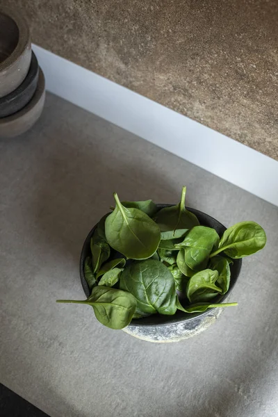 Čerstvý špenát na misce moderní nádobí v kuchyni — Stock fotografie