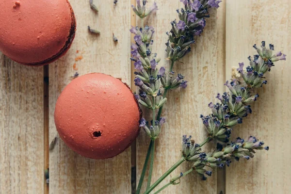 Macarons roses et fleurs naturelles sur table en bois clair — Photo