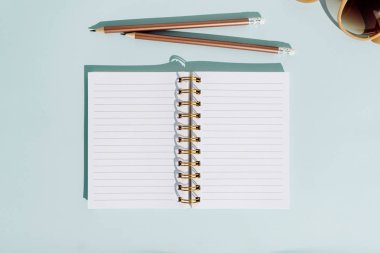 Yaz tatili için düz döşeme defter kalem ve güneş gözlüğü. Aqua