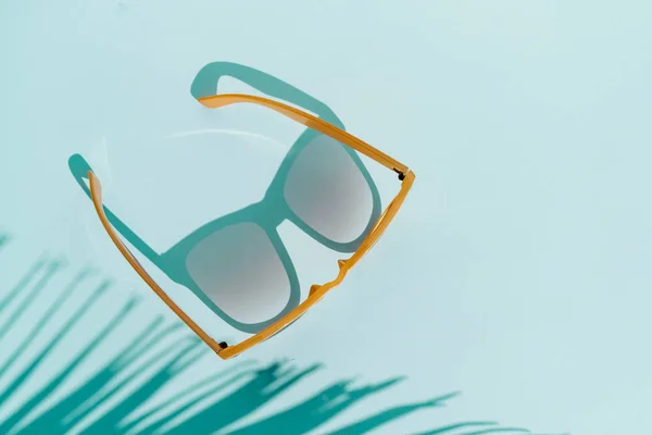 Gafas de sol de vista superior sobre fondo turquesa con luz solar y sh —  Fotos de Stock