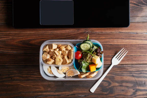 Comida saludable en la lonchera en la mesa de trabajo con portátil Imagen de archivo