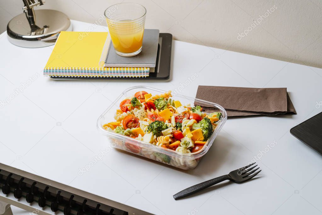 Healthy food in lunch box, on working table with laptop