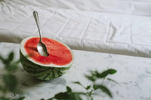 Media sandía fresca, con cuchara en la mesa de la sala de estar — Foto de Stock