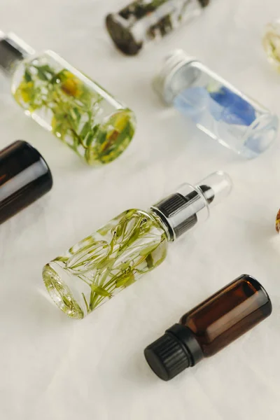 Průhledné láhve základního oleje s čerstvými bylinkami. — Stock fotografie