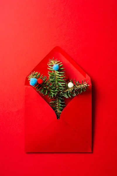 Red envelope with fir tree branches and baubles on pink backgrou — Stock Photo, Image