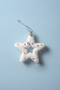 Pastel mavi arka planda parlak beyaz Noel yıldızı, minimal eş