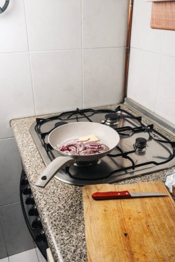 Mutfak ateşinde kırmızı soğan ve tereyağlı tava.