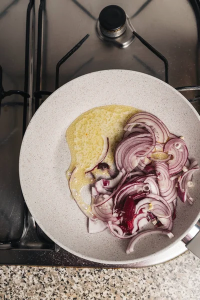 skillet with chopped red onion and butter on the kitchen fire