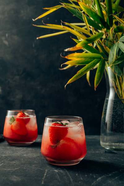 two strawberry cocktail with ice on dark background