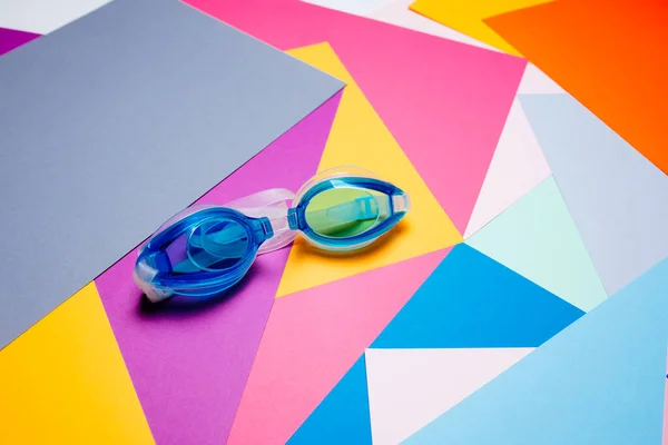 Gafas de natación azules, con correa de goma sobre fondo geométrico multicolor . —  Fotos de Stock