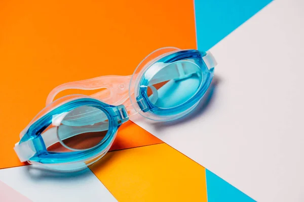 Gafas de natación azules, con correa de goma sobre fondo geométrico multicolor . —  Fotos de Stock
