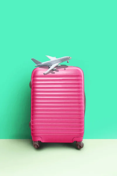 Pinkfarbener Koffer und Flugzeugmodell, minimales kreatives Reisekonzept. — Stockfoto