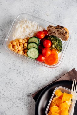 Beslenme çantasında sağlıklı yiyecekler, çalışma masasında. Nohut, brokoli, domates ve havuçlu Basmati pilavı tatlı olarak da ekmek ve meyve. İş yerinde yemek yemek. Ofiste ya da çalışma yerinde ev yapımı yemek konsepti