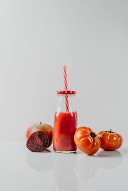 Kırmızı elmalar, domatesler ve olgunlaşmış elmalar, domatesler ve pancarlarla çevrili pipetli kırmızı smoothie içeceği. Sağlıklı vücut ve zihin için detoks diyeti. sağlıklı gıda kavramı.