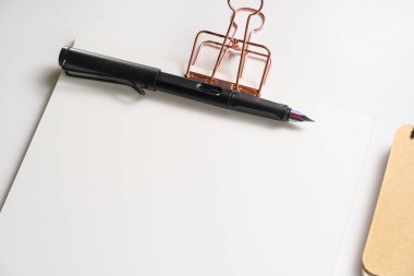 Altın klipsli pano, markalaştırma kırtasiye maketi ve ışık arka planında holografik uçlu dolmakalem. Kurumsal modern ögeler