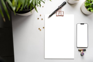 Üst görüntü panosu, mobil şablon ve masadaki yeşil bitkiler. Çalışma alanı aksesuarları ile markalaşma 