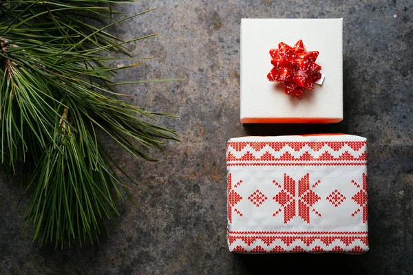 圣诞礼品盒 用喜庆的纸和红色的带子包裹着 周围环绕着松枝 背景是深蓝色的 圣诞节在家里的概念 — 图库照片