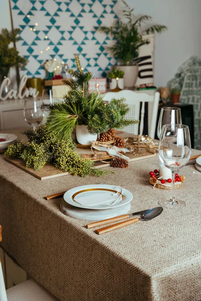 家喻户晓的圣诞餐桌布置 装饰着松树枝条和乡村桌布 客厅里装饰着欧洲风格的圣诞彩灯 — 图库照片