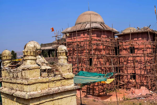 Stock photo of architectural and renovation site of old hindu temple,bamboo scaffolding on red color painted temple building . Picture captured under bright sunlight at Naikba Mandir patan, satara. — Stock Photo, Image