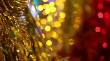 Noel ve Yılbaşı tatil kutlaması. Altın Noel tinsel çelenk süsleri esintiyle üfleme. Bulanık Noel ışıkları yanıp sönen arka planda.
