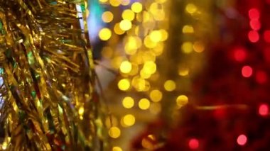Noel ve Yılbaşı tatil kutlaması. Altın Noel tinsel çelenk süsleri esintiyle üfleme. Bulanık Noel ışıkları yanıp sönen arka planda.