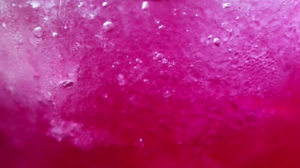 ドリンク詳細の抽象的な美しさ 赤いソーダのアイスと冷たい風の吹くガラス 砕いた氷と炭酸の泡が美しいテクスチャー パターンを作成します — ストック動画