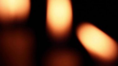 Bulanık yanan mum alevlerinin yakını yanıp sönüyor ve geceleri rüzgarda sallanıyor.