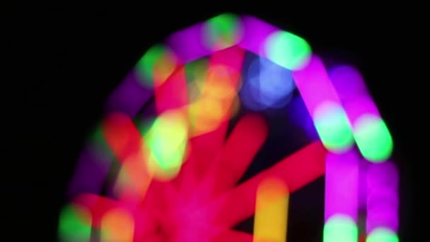 Grande roue déconcentrée avec la décoration colorée d'éclairage de lampe fluorescente tourne lentement à la foire d'amusement de nuit .