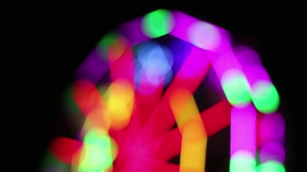 Grande roue déconcentrée avec la décoration colorée d'éclairage de lampe fluorescente tourne lentement à la foire d'amusement de nuit .