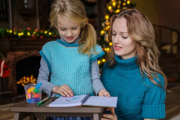 Mamá y su hija pasan tiempo libre juntos en la sala de estar en el árbol de Navidad. sorteo Fotos de stock libres de derechos