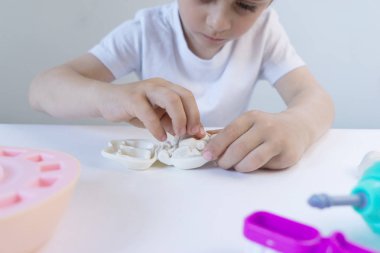 Sevimli küçük çocuk çok renkli plasticine ile oynuyor. Oyuncaklarla oynayan çocuk Diş Aletleri. Yüz ifadesi. Çocuk yaratıcılığı.